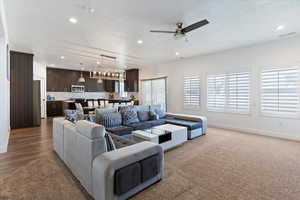 Living room with a textured ceiling, ceiling fan, carpet, and recessed lighting