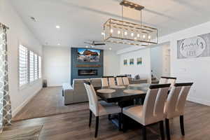 Dining space featuring a large fireplace, stairway, recessed lighting, dark wood-type flooring, and a ceiling fan