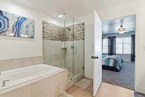 Bathroom with light tile patterned flooring, a shower stall, a bath, ensuite bath, and ceiling fan