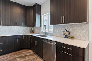 Kitchen featuring dark brown cabinets, stainless steel dishwasher, modern cabinets, and light wood finished floors