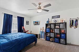 Carpeted bedroom with ceiling fan and a textured ceiling