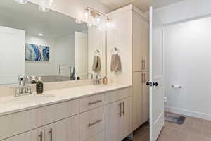 Full bath with light tile patterned floors and double vanity