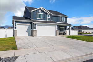 Craftsman house with board and batten siding, concrete driveway, an attached garage, and brick siding