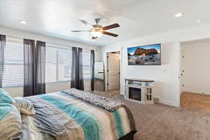 Carpeted bedroom with a ceiling fan, a lit fireplace, a textured ceiling, and recessed lighting