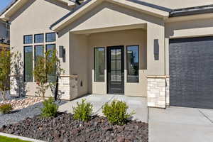 Property entrance featuring stone siding, stucco siding, and a garage