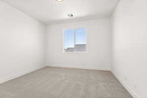 Carpeted spare room featuring baseboards
