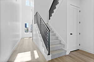 Stairs featuring healthy amount of natural light, a high ceiling, and wood finished floors