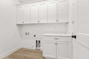 Washroom with light wood-style flooring, hookup for a gas dryer, washer hookup, cabinet space, and hookup for an electric dryer