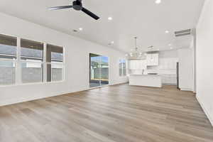Unfurnished living room with recessed lighting, light wood finished floors, a chandelier, and a ceiling fan