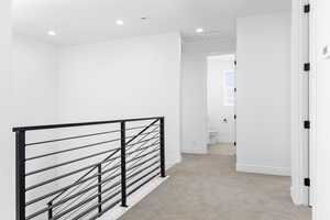 Hallway with light carpet, recessed lighting, and an upstairs landing