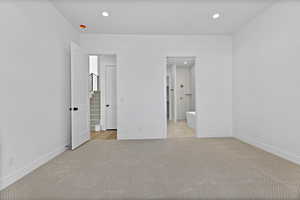 Unfurnished bedroom featuring light colored carpet, recessed lighting, and connected bathroom