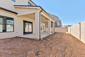 Rear view of house featuring stucco siding, a patio area, and a fenced backyard