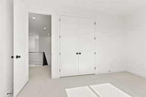 Unfurnished bedroom featuring light carpet, recessed lighting, and a closet