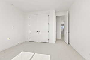Unfurnished bedroom with light colored carpet and a closet