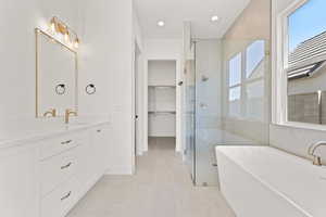 Bathroom featuring a freestanding tub, a shower stall, a spacious closet, vanity, and recessed lighting