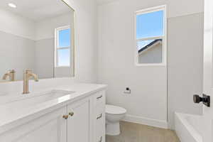 Full bath with plenty of natural light, vanity, a tub to relax in, and light tile patterned floors