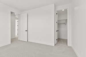 Unfurnished bedroom featuring light colored carpet, a walk in closet, and recessed lighting