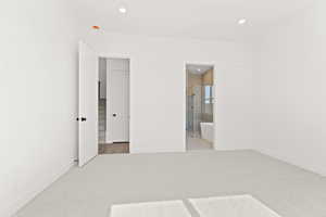 Unfurnished bedroom with light carpet, recessed lighting, and ensuite bath