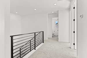 Hall featuring light colored carpet, recessed lighting, and an upstairs landing