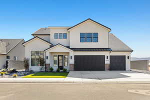 View of front of home with driveway, stucco siding, brick siding, and a garage
