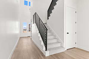 Staircase featuring healthy amount of natural light, a towering ceiling, and wood finished floors