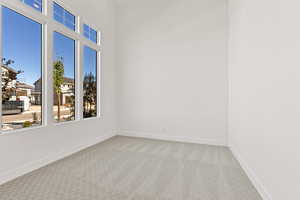 Unfurnished room featuring light carpet and baseboards