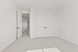 Unfurnished bedroom with light carpet and a closet