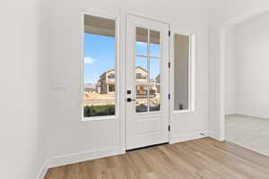 Doorway to outside with healthy amount of natural light and wood finished floors
