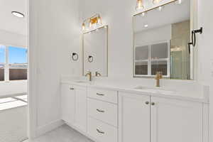 Bathroom with double vanity, a stall shower, and light tile patterned floors