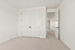 Unfurnished bedroom with light carpet and a closet