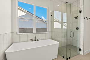 Full bath featuring a freestanding tub, a shower stall, tile walls, and tile patterned flooring