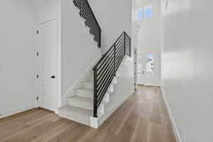 Stairway featuring plenty of natural light, wood finished floors, and a towering ceiling