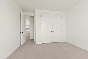 Unfurnished bedroom featuring light colored carpet and a closet