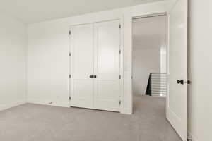 Unfurnished bedroom featuring light carpet and a closet