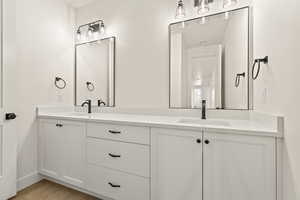 Full bathroom with double vanity and light wood-style flooring