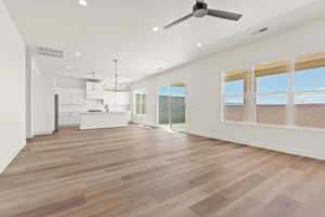 Unfurnished living room featuring recessed lighting, light wood finished floors, a chandelier, and a ceiling fan