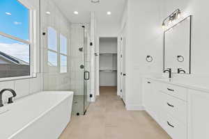 Bathroom with a freestanding tub, a stall shower, vanity, recessed lighting, and a walk in closet