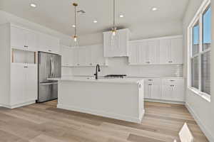 Kitchen with white cabinets, freestanding refrigerator, recessed lighting, backsplash, and light wood-type flooring