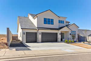 View of front of home featuring concrete driveway, stucco siding, an attached garage, and a standing seam roof