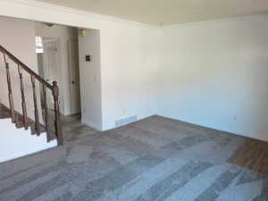 Carpeted spare room with stairway and ornamental molding