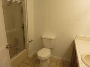 Bathroom featuring vanity, light tile patterned flooring, and combined bath / shower with glass door