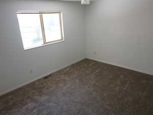 Empty room with dark carpet and baseboards