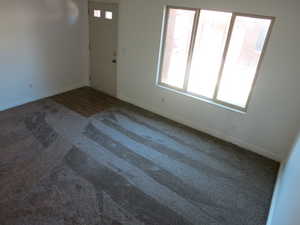 Spare room with plenty of natural light and dark colored carpet