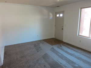 Carpeted entrance foyer with baseboards and ornamental molding