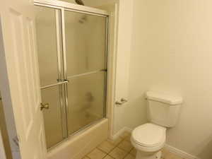 Bathroom featuring tile patterned floors and shower / bath combination with glass door