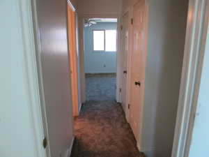 Corridor with dark carpet and baseboards
