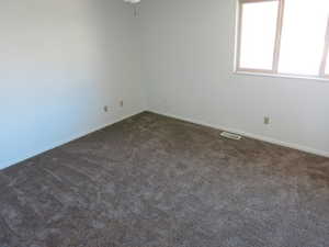 Spare room with dark carpet and baseboards