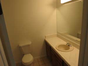Half bath with light tile patterned flooring and vanity
