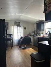 Kitchen with freestanding refrigerator, light wood-style flooring, a textured ceiling, stainless steel dishwasher, and lofted ceiling