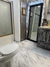 Full bath with vanity, light marble finish flooring, and combined bath / shower with glass door